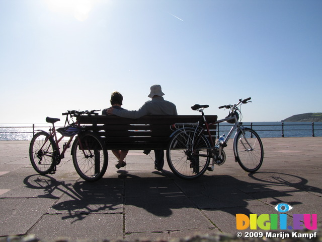 SX08990 Jenni and Marijn sitting on bench with push bikes at Penzance promenade